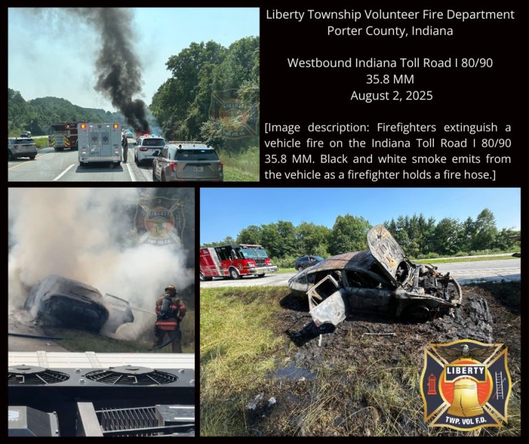 Firefighters from the Liberty Township Volunteer Fire Department extinguish a burned vehicle on the side of a highway. Black and white smoke rises as multiple emergency vehicles secure the scene near scorched grass by the road.
