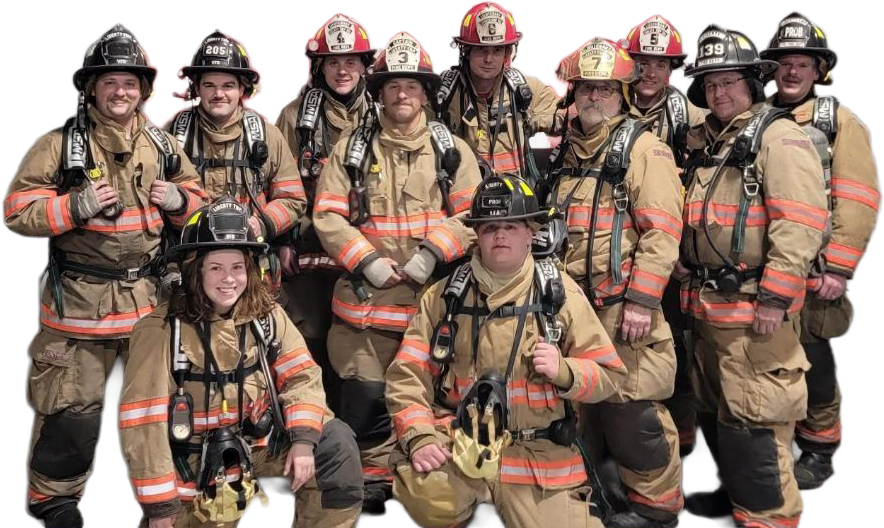 A group of eleven Liberty Township Volunteer Fire Department firefighters in full gear and helmets pose together, smiling for the camera. Their uniforms have reflective stripes, and some are kneeling in front while others stand behind them.